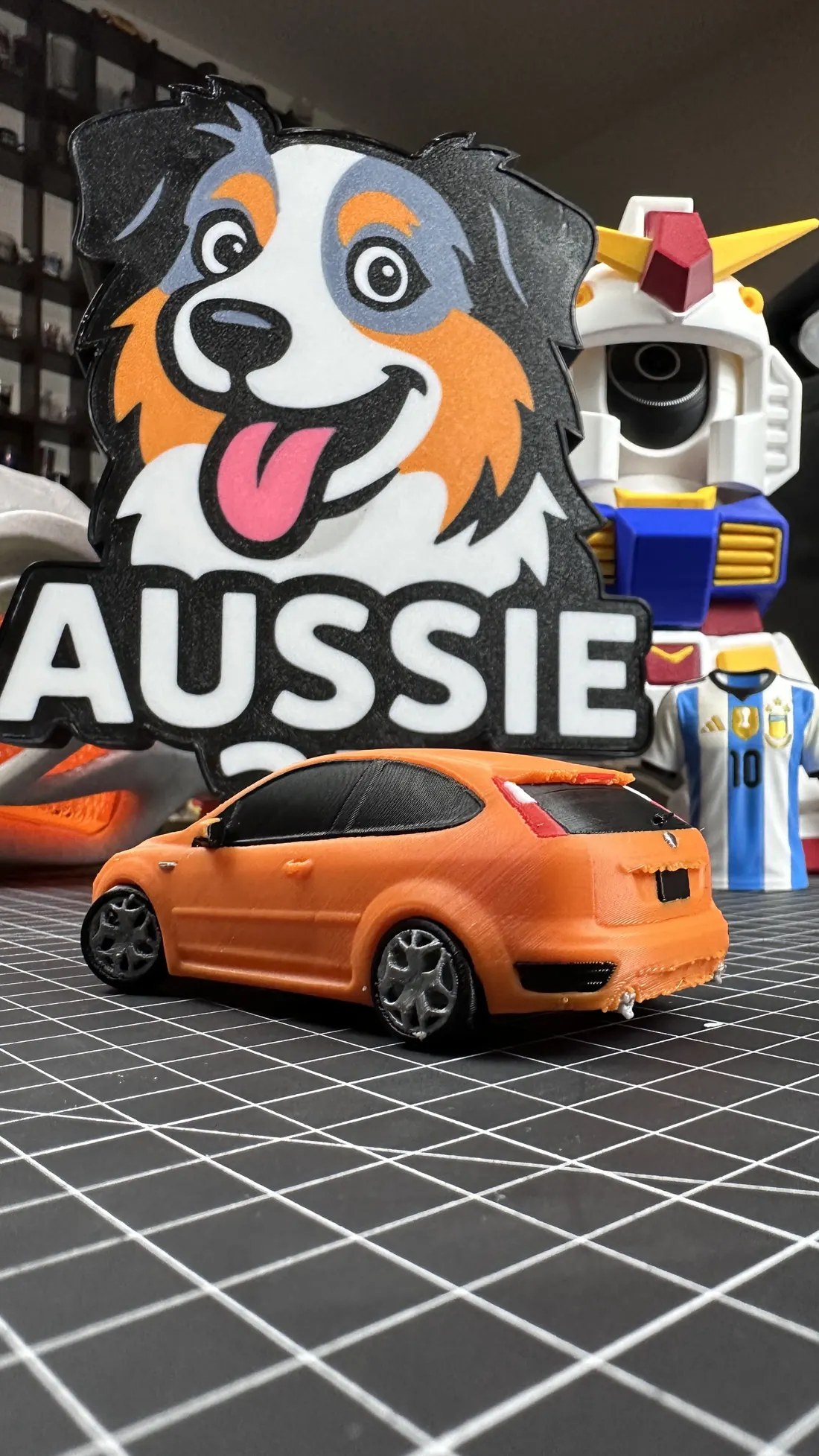 Letrero de la marca Aussie 3D impreso en 3D junto a un auto a escala